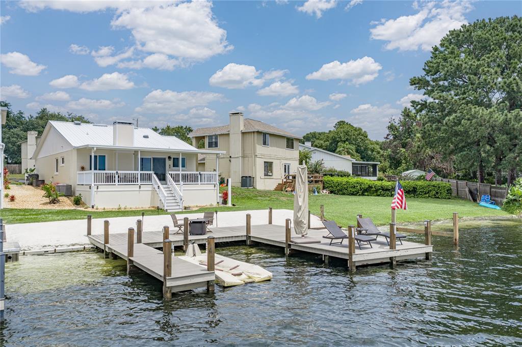 A white house with a deck overlooks a wooden dock on a lake — 679 LAKE DEXTER CIRCLE, WINTER HAVEN, FL