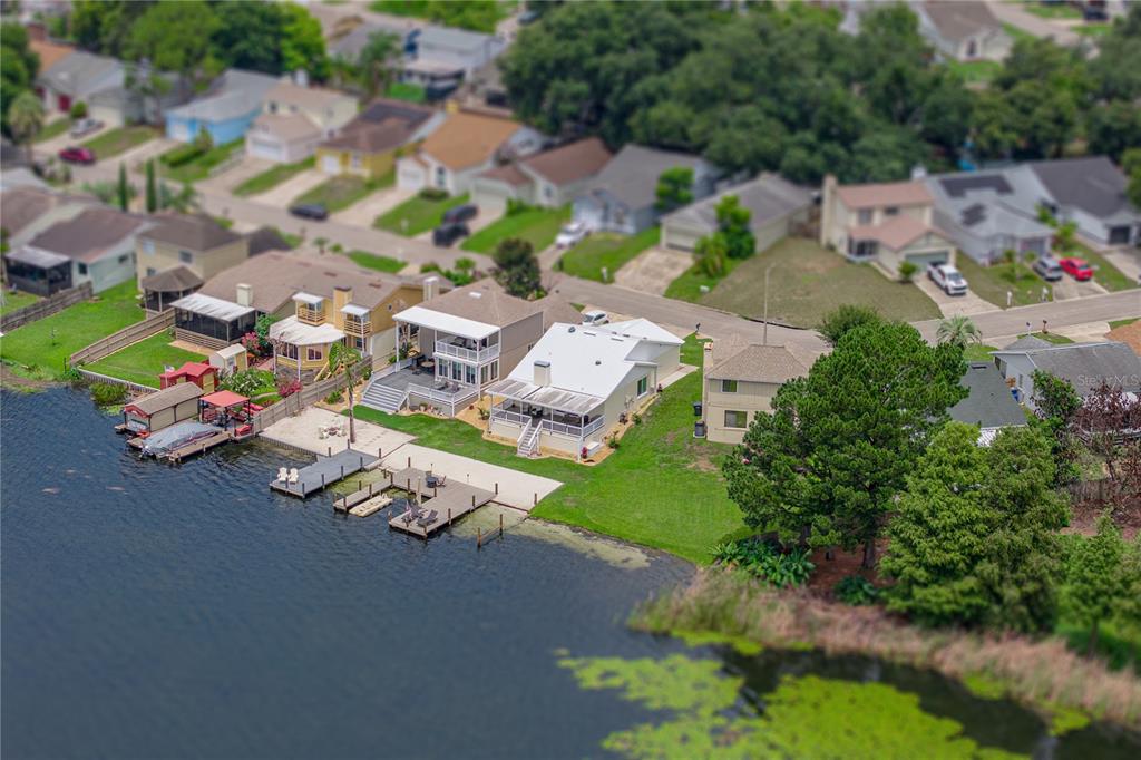 An aerial view shows several waterfront houses with private docks along a lake — 679 LAKE DEXTER CIRCLE, WINTER HAVEN, FL