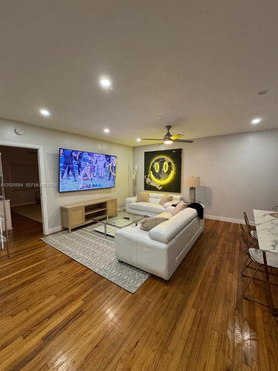 A living room features a white sectional sofa, a wall-mounted television, and hardwood flooring — 101 Collins Ave # 3, Miami Beach FL 33139, MIAMI BEACH, FL