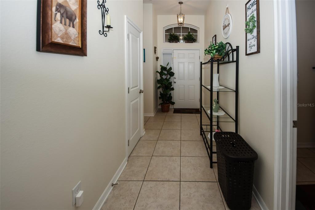 A tiled entryway features a white front door, a black metal shelf, and wall decor — 14148 FINSBURY DRIVE, SPRING HILL, FL