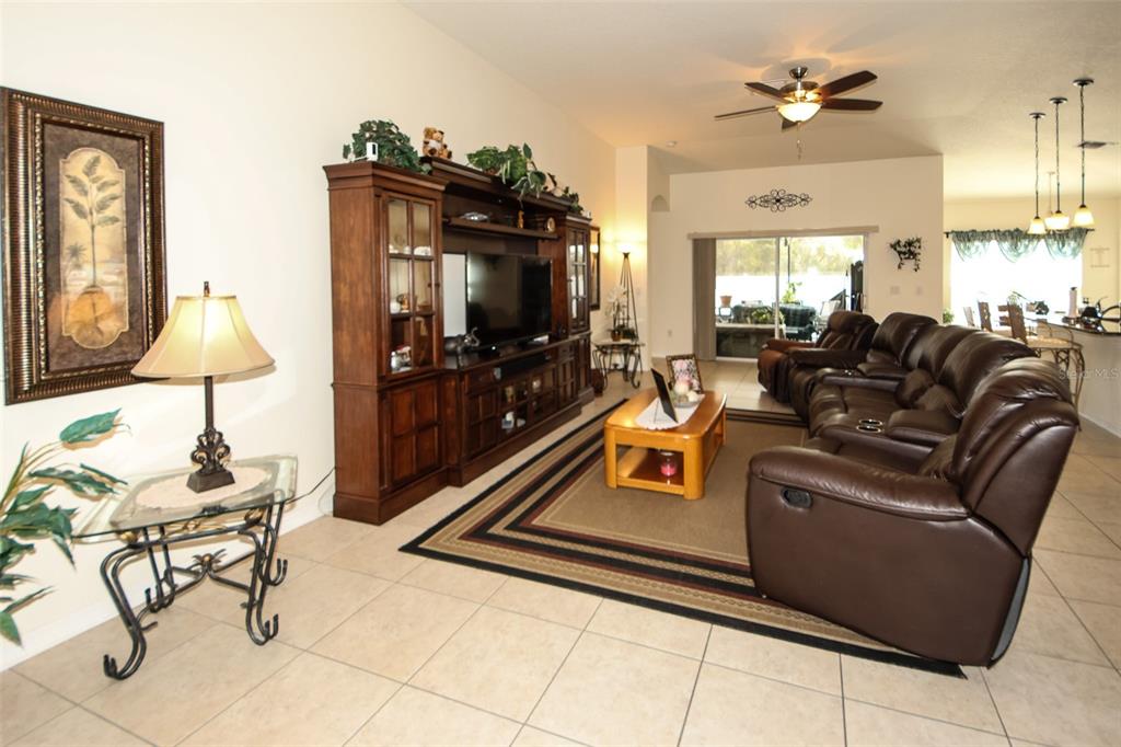 A living room features tile flooring, a large entertainment center, and brown leather reclining furniture — 14148 FINSBURY DRIVE, SPRING HILL, FL