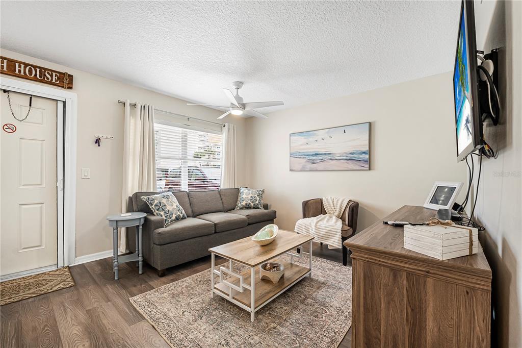 A living room features a gray sofa, a coffee table, and a wall-mounted television — 3724 S ATLANTIC AVENUE UNIT 30, DAYTONA BEACH, FL