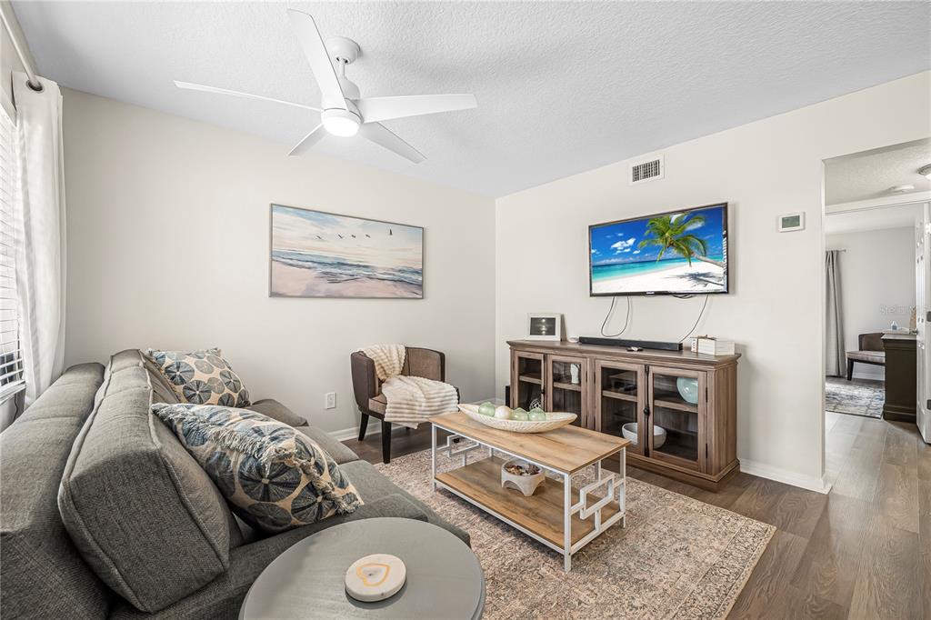 A living room features a gray sofa, a wooden coffee table, and a wall-mounted television — 3724 S ATLANTIC AVENUE UNIT 30, DAYTONA BEACH, FL