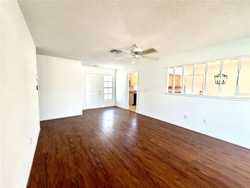An empty living room features wood-look flooring, white walls, and a ceiling fan — 8212 101ST COURT, SEMINOLE, FL