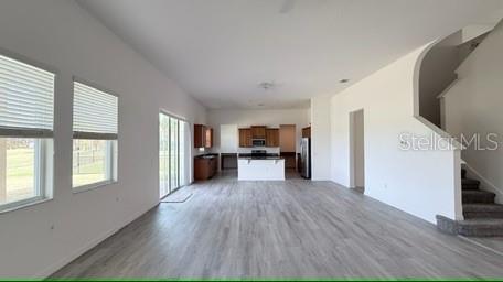 An open-concept living area features light wood-look flooring, white walls, and a kitchen in back — 3879 SHORESIDE DRIVE, KISSIMMEE, FL