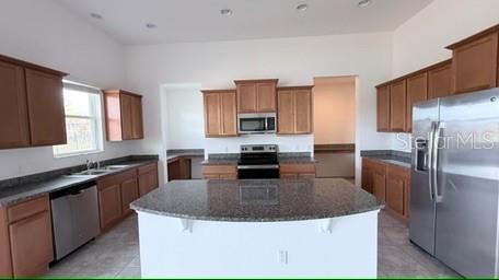 A kitchen features wood cabinets, granite countertops, a central island, and stainless steel appliances — 3879 SHORESIDE DRIVE, KISSIMMEE, FL