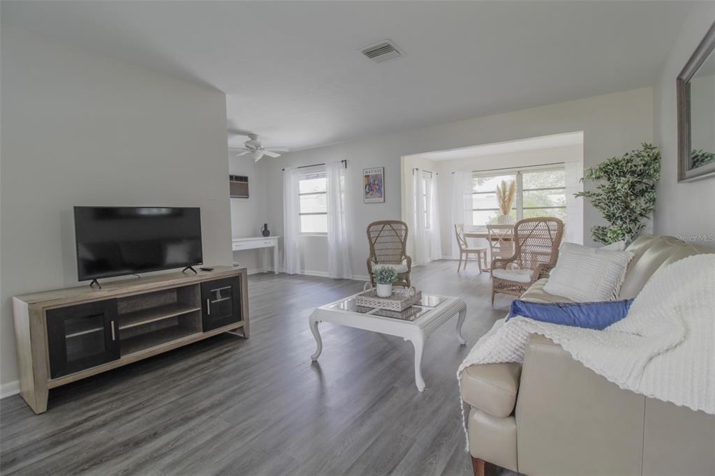A living room features light gray wood-look flooring, a television console, and wicker accent chairs — 2338 NASH STREET, CLEARWATER, FL