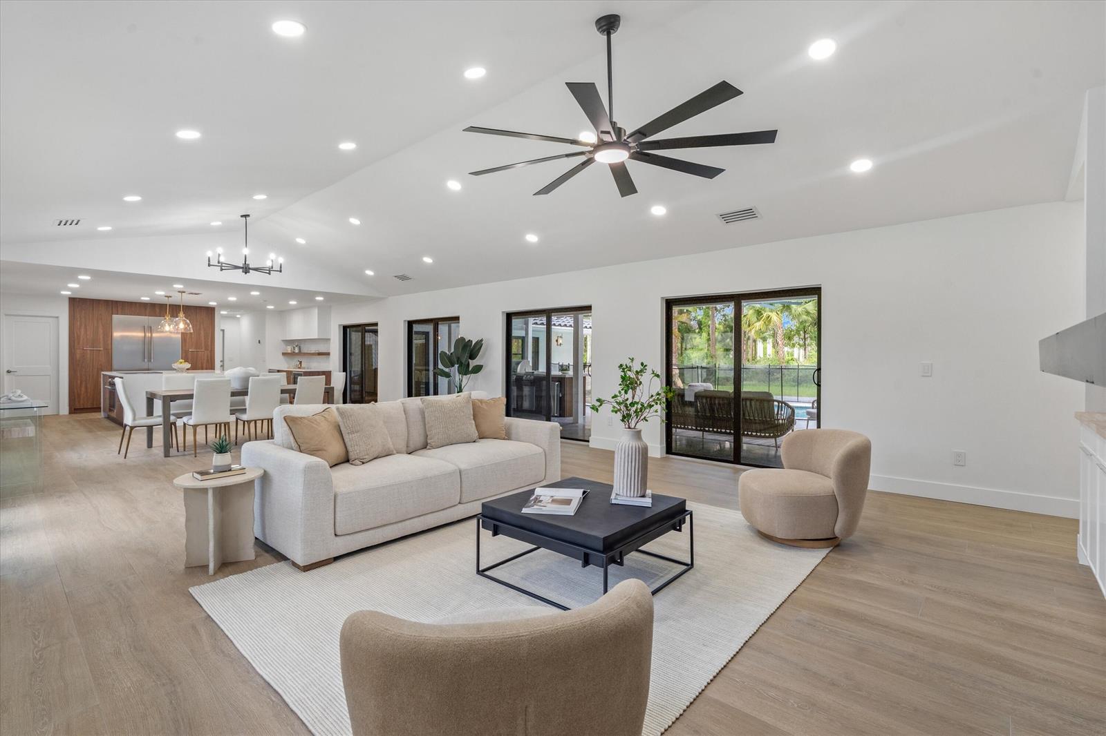A bright, open-concept living and dining area features light wood floors and a vaulted ceiling — 14756 Stirrup Lane, Wellington FL 33414, WELLINGTON, FL