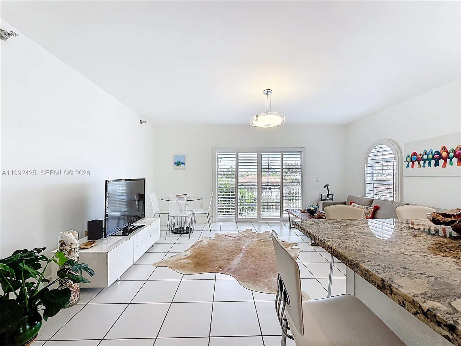 A kitchen features white cabinets, stainless steel appliances, and granite countertops with a tiled floor — 9008 Collins Ave # 303, Surfside FL 33154, SURFSIDE, FL