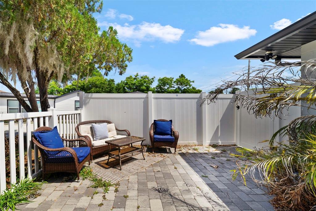 A paved patio features wicker furniture with blue cushions enclosed by a white vinyl fence — 4521 EDGEWATER DRIVE UNIT 1, ORLANDO, FL