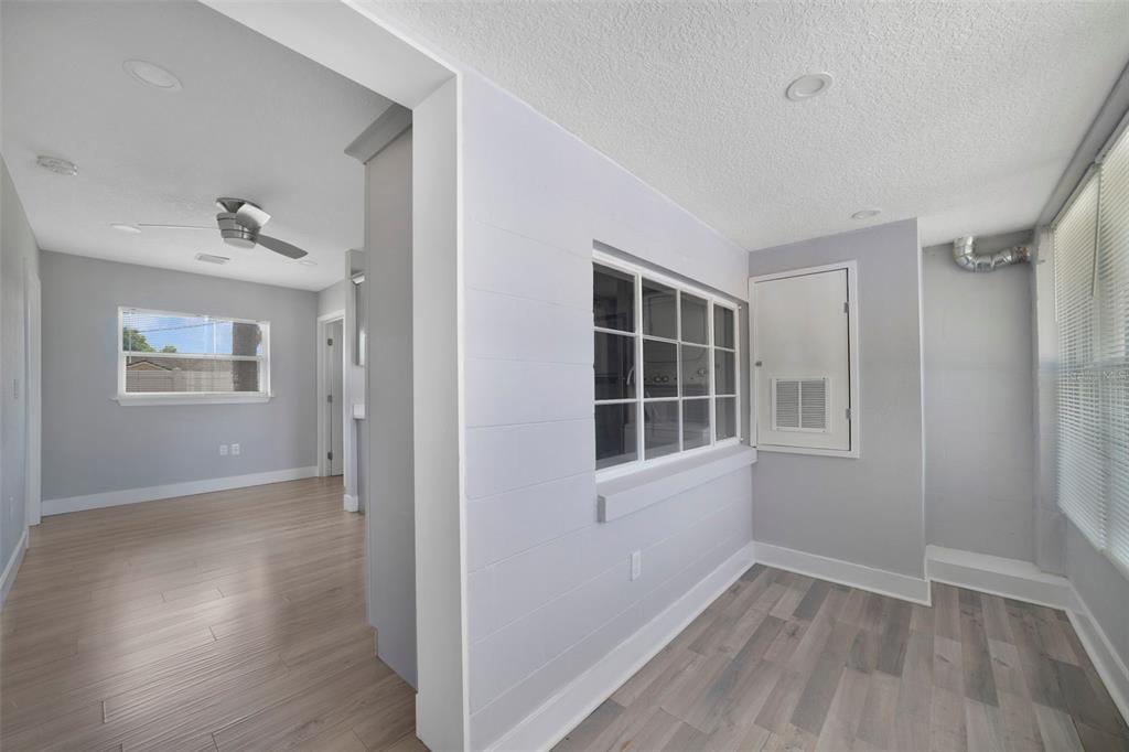 A light gray room features wood-look flooring, a shiplap wall, and a windowed pass-through — 4521 EDGEWATER DRIVE UNIT 1, ORLANDO, FL