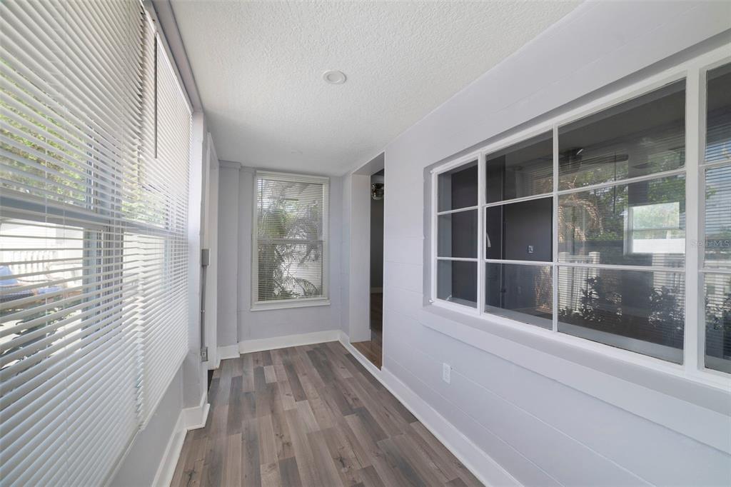 A sunroom with light gray walls, wood-look flooring, and large windows with white blinds — 4521 EDGEWATER DRIVE UNIT 1, ORLANDO, FL