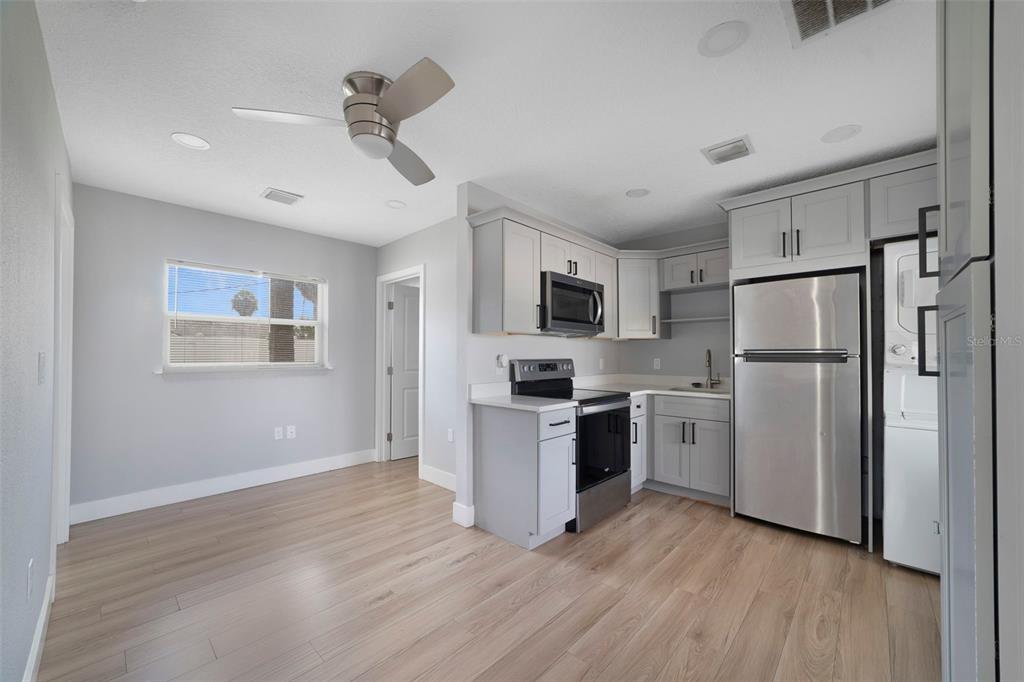 A kitchen and dining area with light gray walls, wood-look flooring, and stainless steel appliances — 4521 EDGEWATER DRIVE UNIT 1, ORLANDO, FL