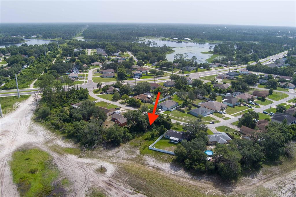 An aerial view shows a residential neighborhood with a red arrow pointing toward a lot — 2599 HILLVIEW CIRCLE, DELTONA, FL