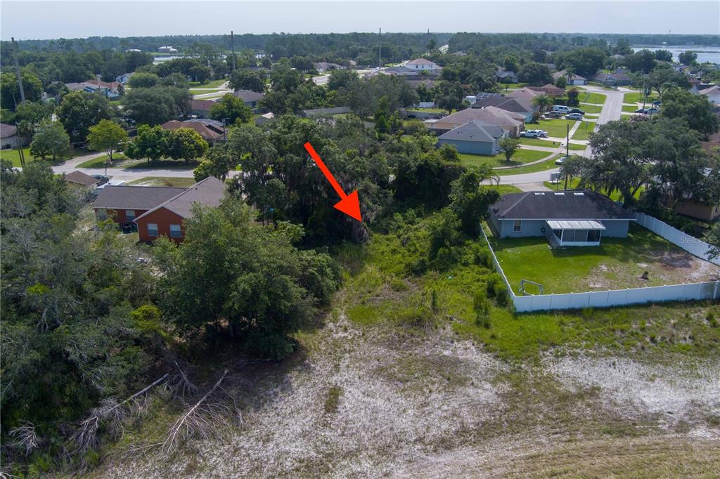 An aerial view shows a vacant, overgrown lot situated between two residential houses — 2599 HILLVIEW CIRCLE, DELTONA, FL