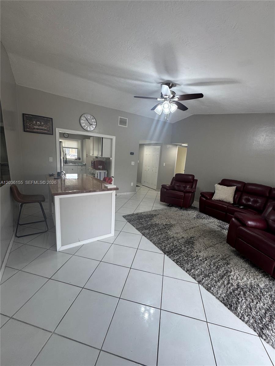 A living room with tile floors, a kitchen island, and red leather furniture — 11504 SW 124th Ct, Miami FL 33186, MIAMI, FL