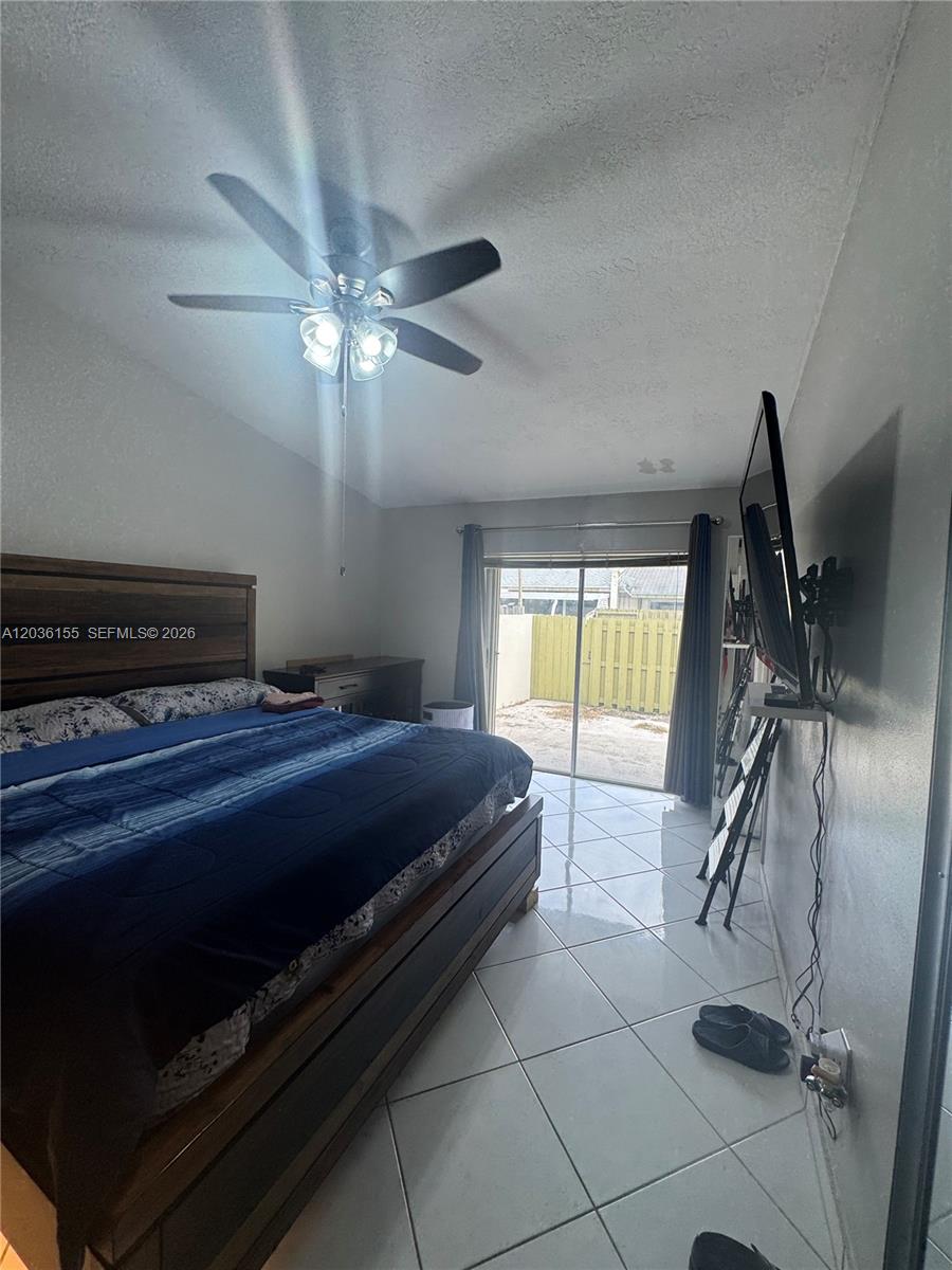 A bedroom features a wooden bed frame, tile flooring, a ceiling fan, and sliding glass doors — 11504 SW 124th Ct, Miami FL 33186, MIAMI, FL