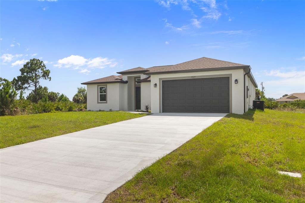 A single-story house with a gray garage door, light-colored stucco exterior, and a concrete driveway — 7329 ATHENS TERRACE, PORT CHARLOTTE, FL