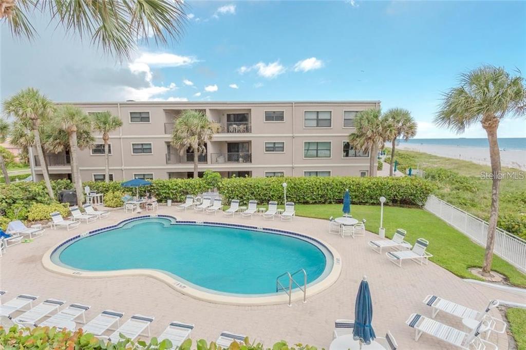 An outdoor swimming pool sits in front of a multi-story apartment building near the beach — 3400 GULF BOULEVARD UNIT 201, BELLEAIR BEACH, FL
