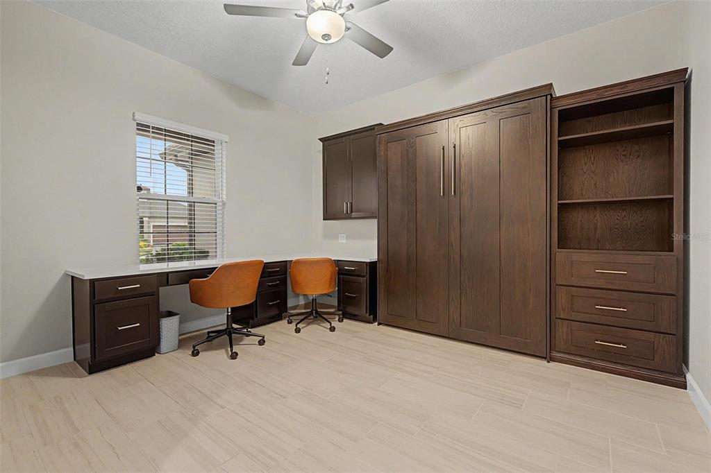 A home office features a built-in Murphy bed, desk space, and dark wood cabinetry — 10460 GABLE DIG LOOP, SAN ANTONIO, FL