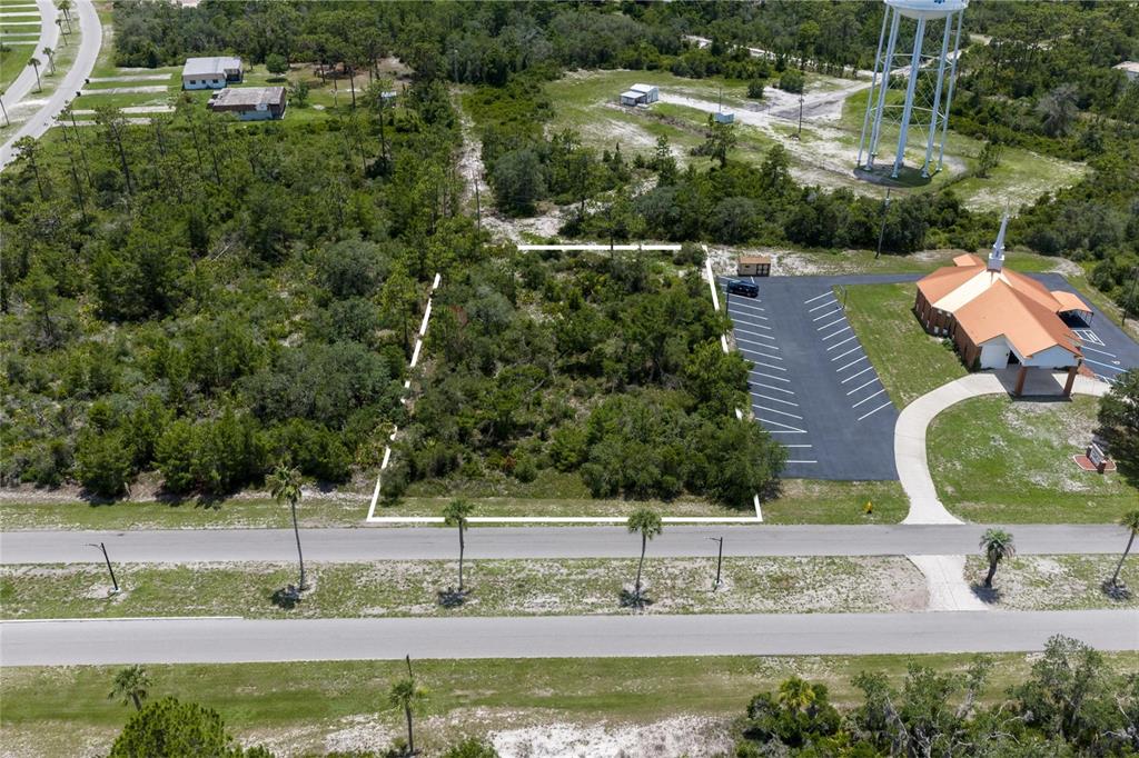 An aerial view shows a vacant, rectangular lot bordered by a road and a church parking lot — PARK AVENUE, INDIAN LAKE ESTATES, FL