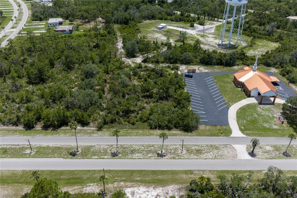 An aerial view shows a church with a parking lot next to a wooded lot — PARK AVENUE, INDIAN LAKE ESTATES, FL