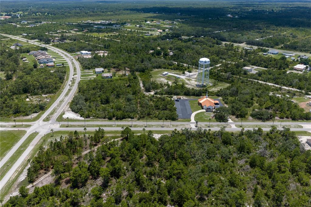 An aerial view shows a church, a water tower, and surrounding wooded lots near roads — PARK AVENUE, INDIAN LAKE ESTATES, FL