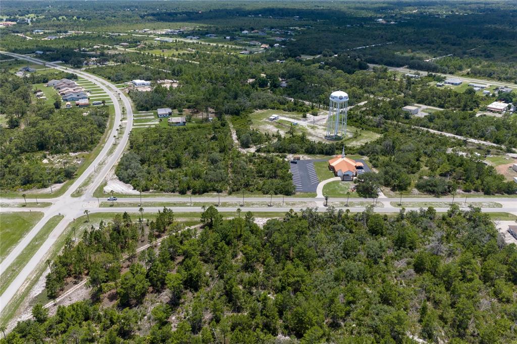 An aerial view shows a church, a water tower, and roads surrounded by wooded land — PARK AVENUE, INDIAN LAKE ESTATES, FL