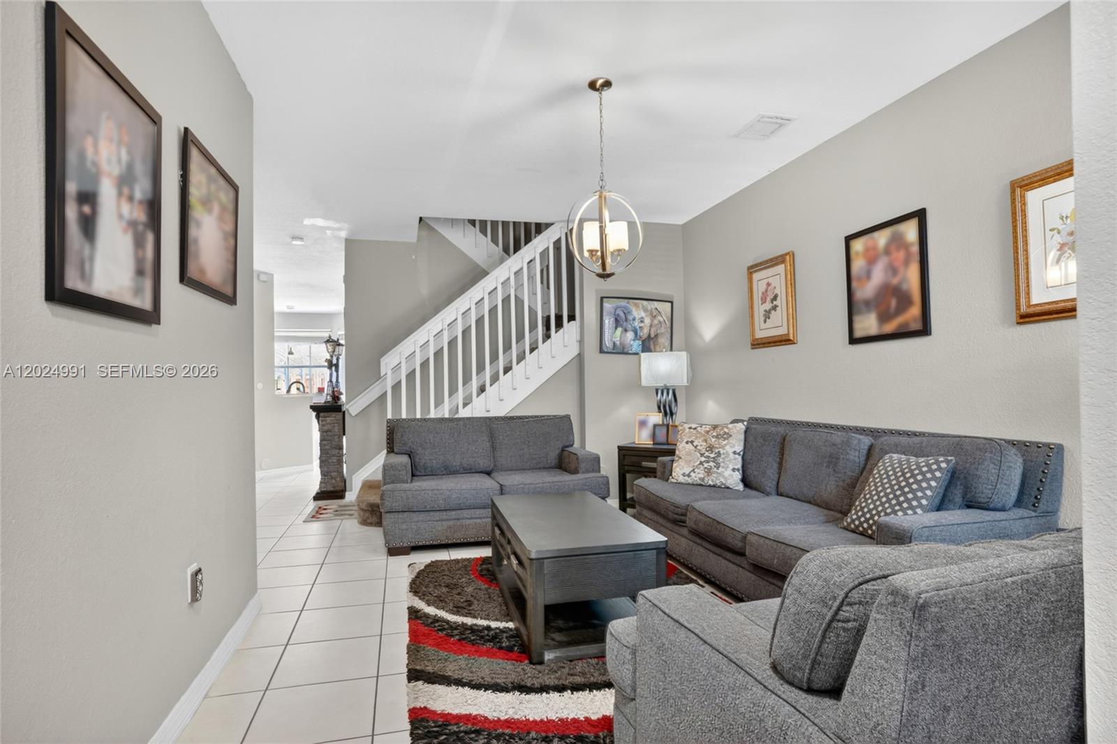 A living room features gray sofas, a coffee table, a rug, and a staircase — 16651 SW 79th Ter, Miami FL 33193, MIAMI, FL