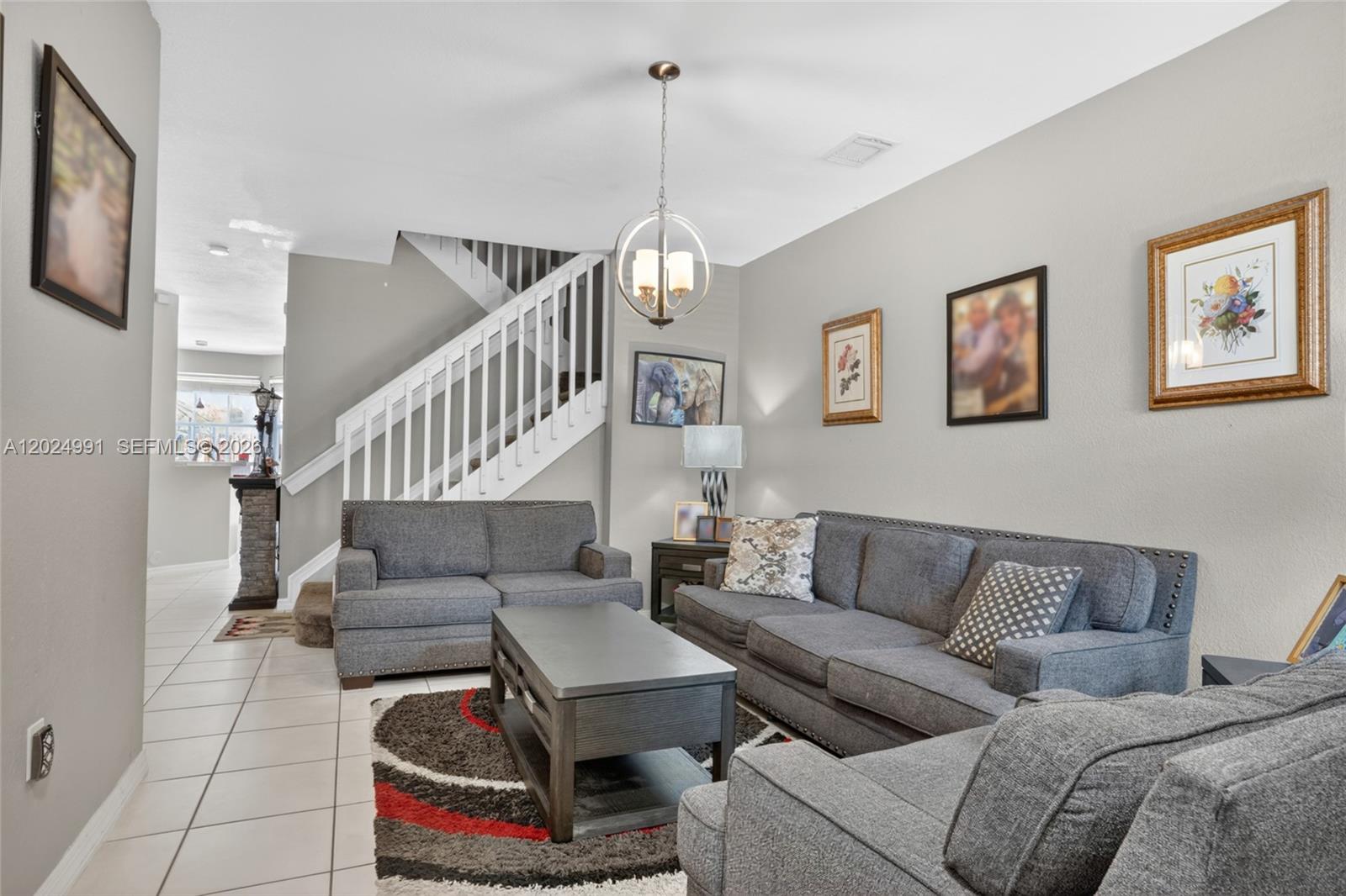 A living room features grey sofas, a coffee table, a staircase, and wall art — 16651 SW 79th Ter, Miami FL 33193, MIAMI, FL