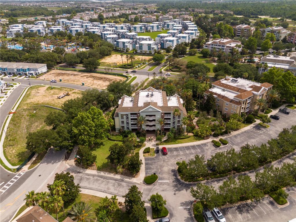An aerial view shows a multi-story residential building surrounded by parking lots and landscaping — 7659 WHISPER WAY UNIT 304, REUNION, FL