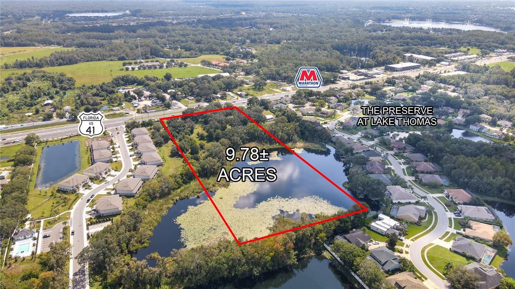 An aerial view shows a 9.78-acre parcel of land bordering a lake and residential neighborhood — 5927 LAND O LAKES BOULEVARD, LAND O LAKES, FL