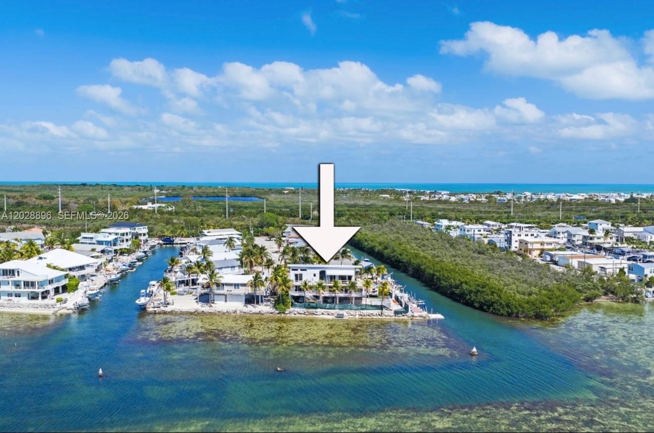 An aerial view shows a waterfront house on a small peninsula surrounded by shallow water — 233 Aberdeen Ct, Tavernier FL 33070, TAVERNIER, FL