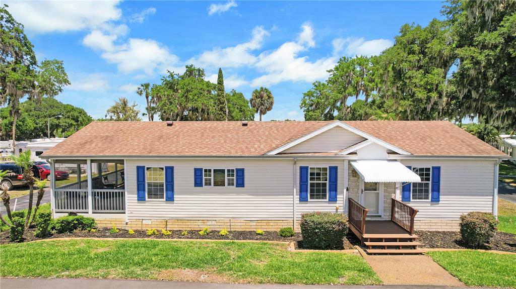 A single-story manufactured home with light siding, blue shutters, and a screened-in porch — 15 RIVERVIEW DRIVE, FRUITLAND PARK, FL