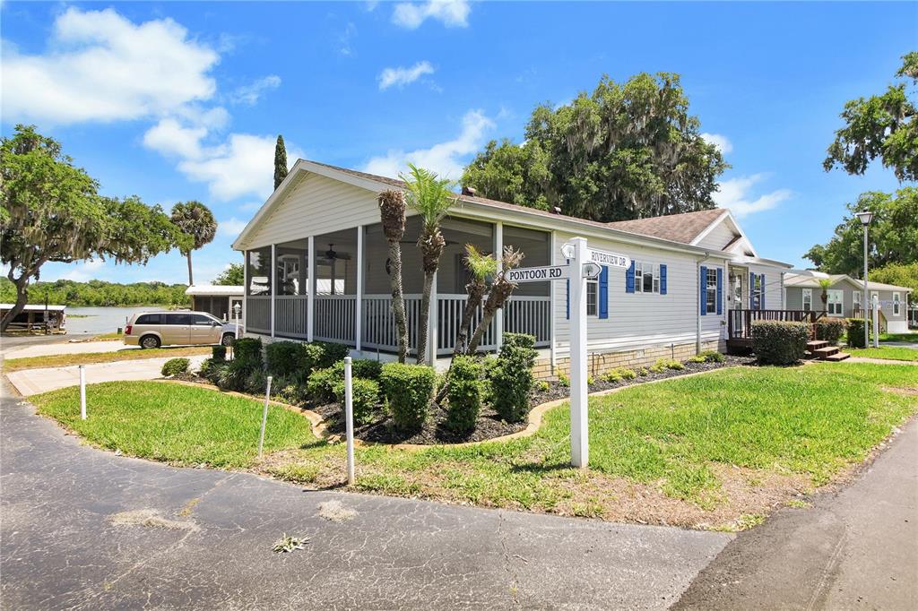 A white house with a screened-in porch sits on a corner lot near water — 15 RIVERVIEW DRIVE, FRUITLAND PARK, FL