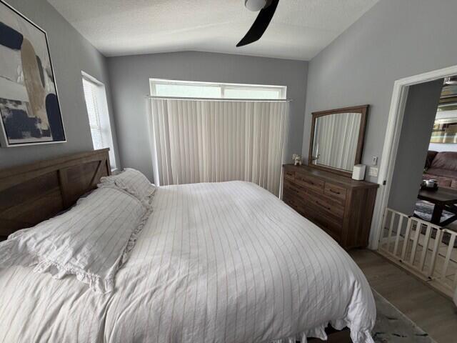 A bedroom features a wooden bed frame, a matching dresser with a mirror, and vertical blinds — 3013 Laurel Ridge Circle, Riviera Beach FL 33404, RIVIERA BEACH, FL