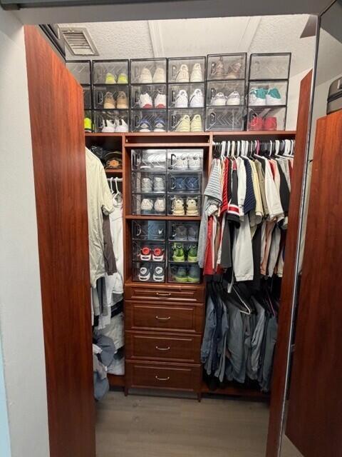 A walk-in closet features wooden shelving, a built-in dresser, and clear plastic shoe storage boxes — 3013 Laurel Ridge Circle, Riviera Beach FL 33404, RIVIERA BEACH, FL