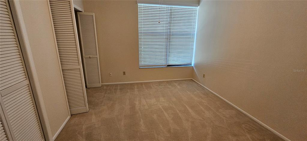 A bedroom features beige carpet, light-colored walls, and a window with white horizontal blinds — 105 LAUREL COVE WAY UNIT 105, WINTER HAVEN, FL