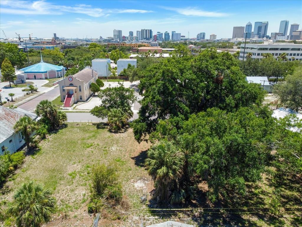 An aerial view shows a vacant lot with large trees next to a church building — 940 E 11TH AVENUE, TAMPA, FL