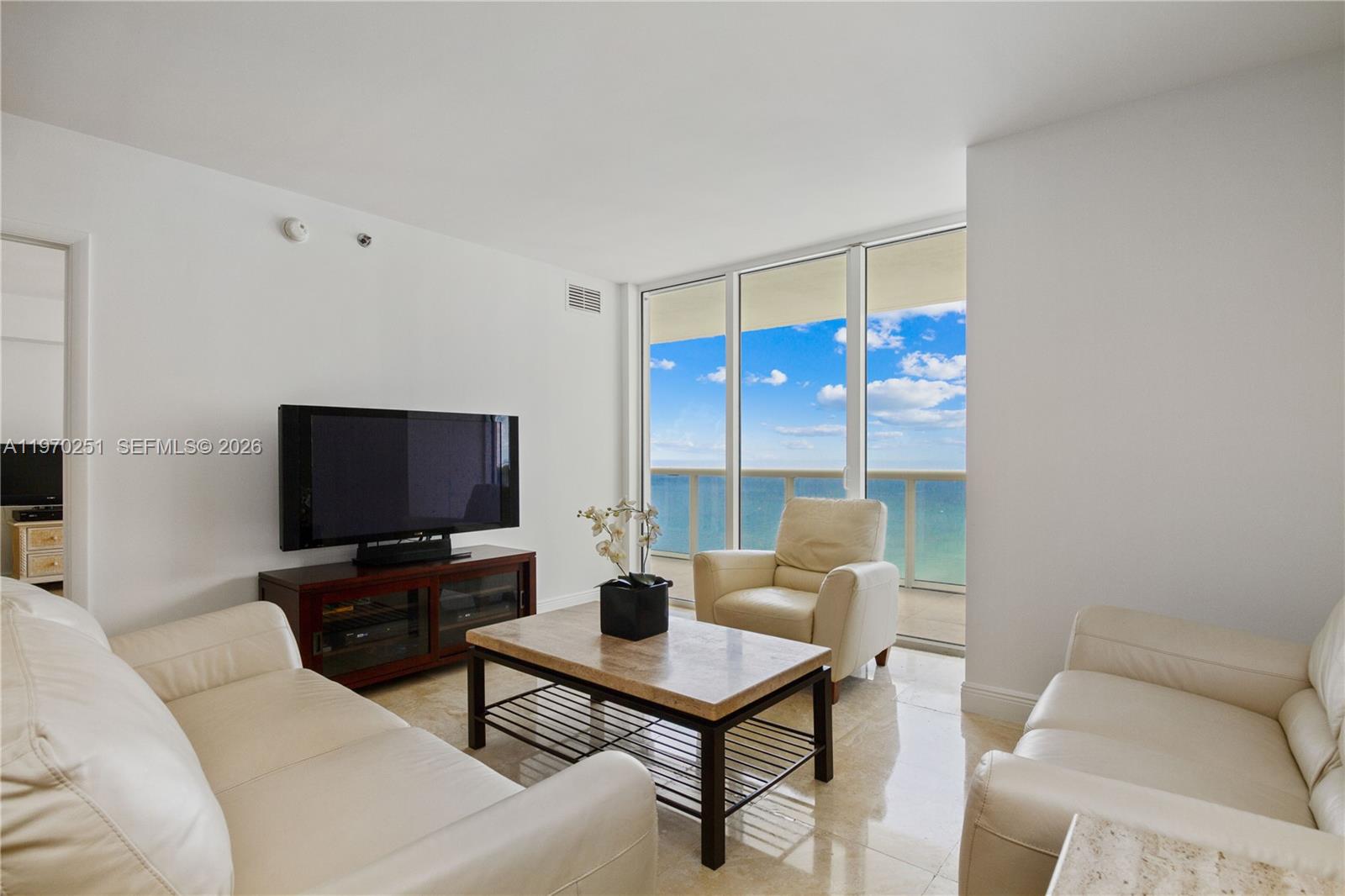 A living room features white leather sofas, a coffee table, and floor-to-ceiling ocean views — 1830 S Ocean Dr # 4204, Hallandale Beach FL 33009, HALLANDALE BEACH, FL
