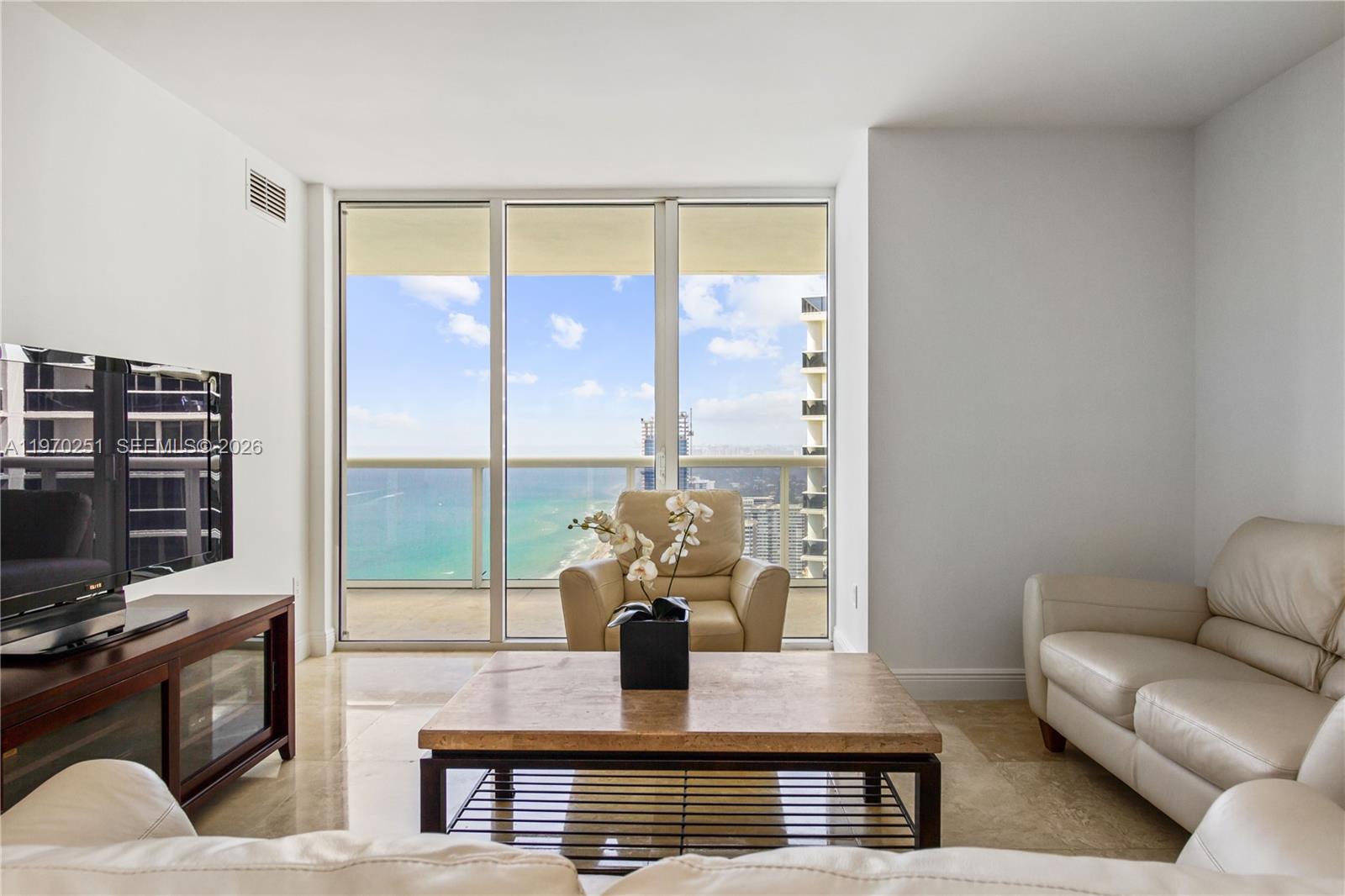 A living room features a television, leather furniture, a coffee table, and floor-to-ceiling ocean views — 1830 S Ocean Dr # 4204, Hallandale Beach FL 33009, HALLANDALE BEACH, FL