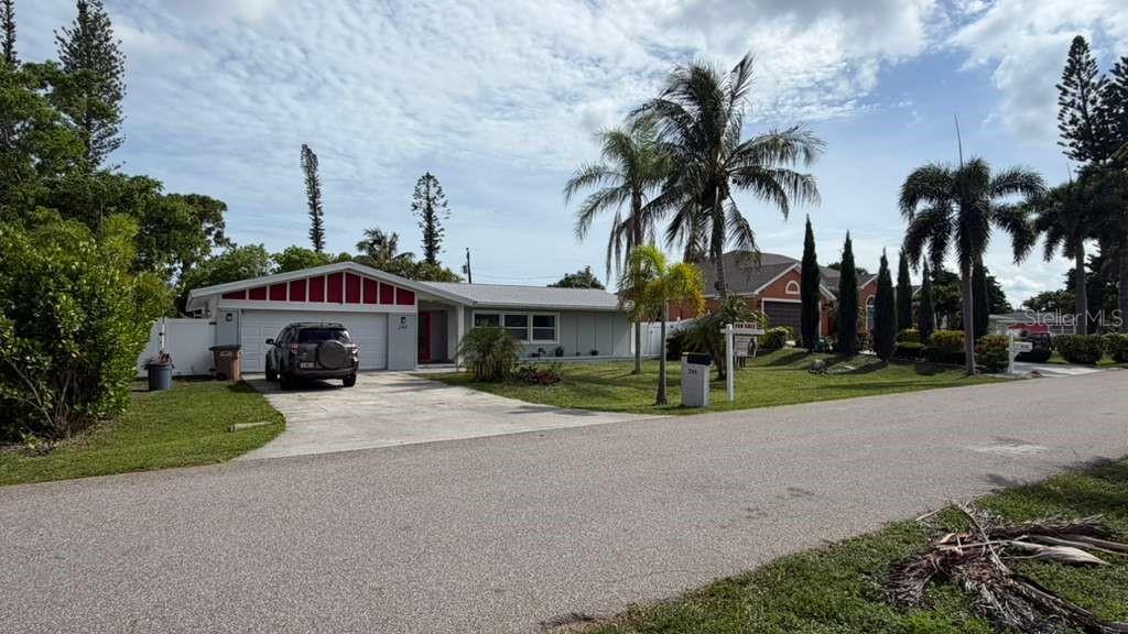 A single-story house with a white exterior, red trim, and a driveway with a parked SUV — 244 SE 46TH STREET, CAPE CORAL, FL