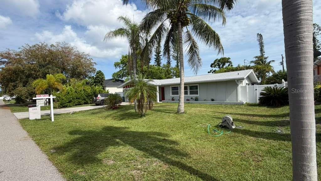 A single-story house with a light-colored exterior, a palm tree, and a for-sale sign — 244 SE 46TH STREET, CAPE CORAL, FL