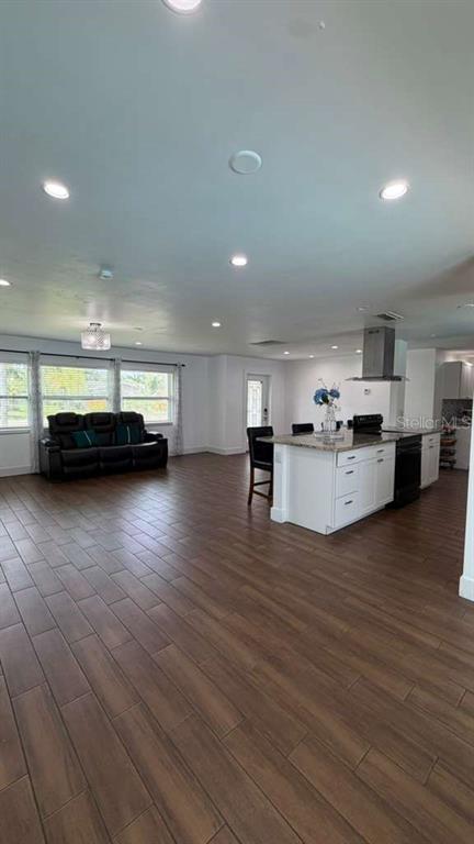 An open-concept living room and kitchen with wood-look tile flooring and white cabinetry — 244 SE 46TH STREET, CAPE CORAL, FL