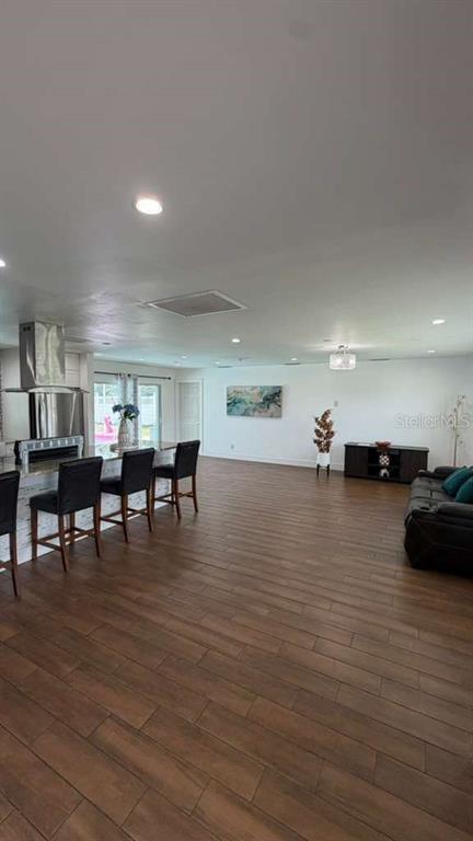 An open-concept kitchen and living area features wood-look tile flooring and a breakfast bar — 244 SE 46TH STREET, CAPE CORAL, FL