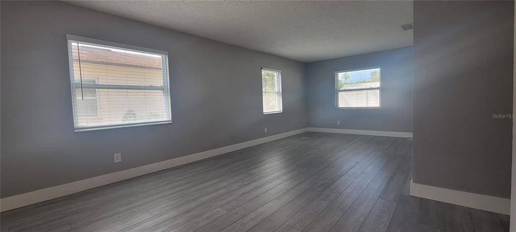 An empty room features gray walls, white trim, and light-colored wood-look flooring — 6625 S WEST SHORE BOULEVARD, TAMPA, FL