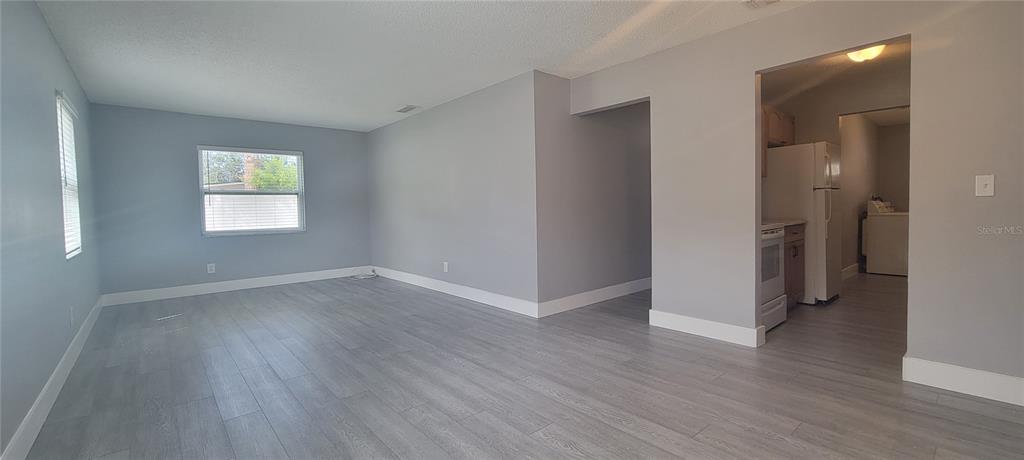 A living room with gray walls, light wood-look flooring, and an adjacent kitchen — 6625 S WEST SHORE BOULEVARD, TAMPA, FL