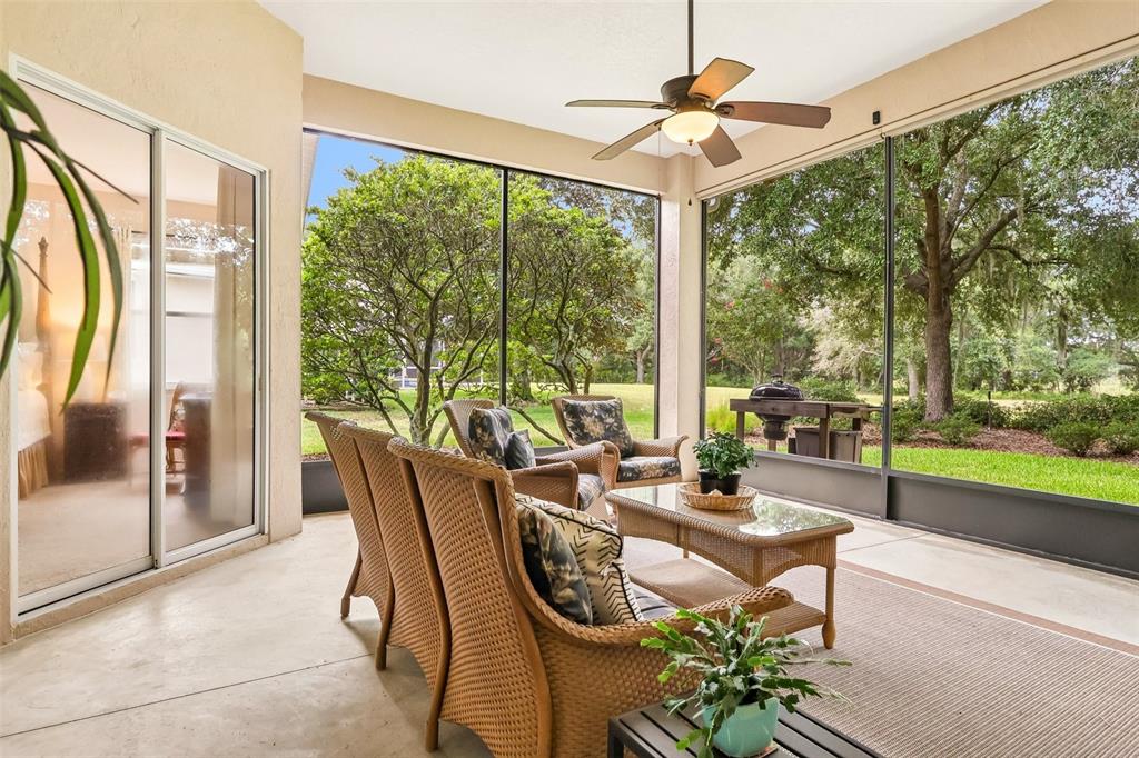 A dining area with a wooden table, chandelier, and sliding glass doors opens to a living room — 20554 QUEEN ALEXANDRA DRIVE, LEESBURG, FL