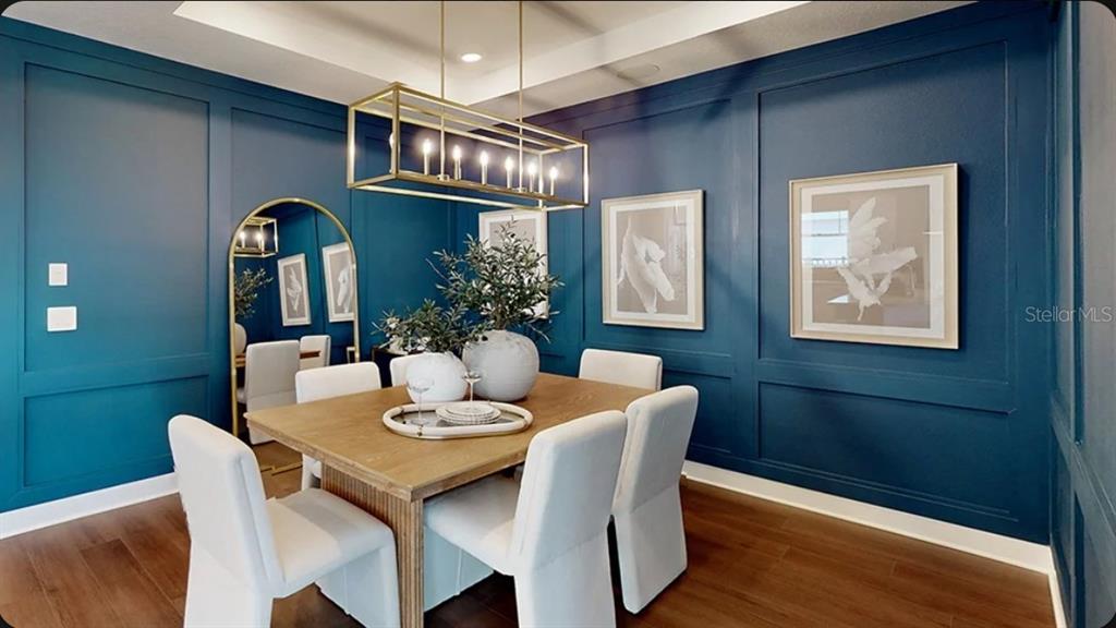 A dining room features deep blue paneled walls, a wooden table, and a gold light fixture — 11275 SILVER TRUMPET LOOP, WINTER GARDEN, FL