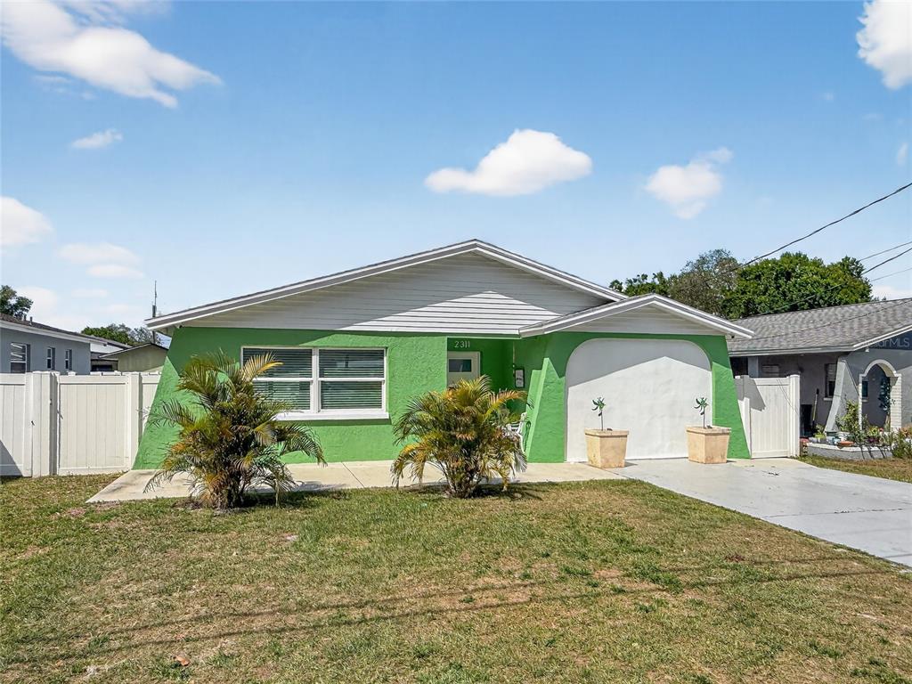 A single-story house with a green stucco exterior, white trim, and a front-facing garage — 2311 W KENTUCKY AVENUE, TAMPA, FL